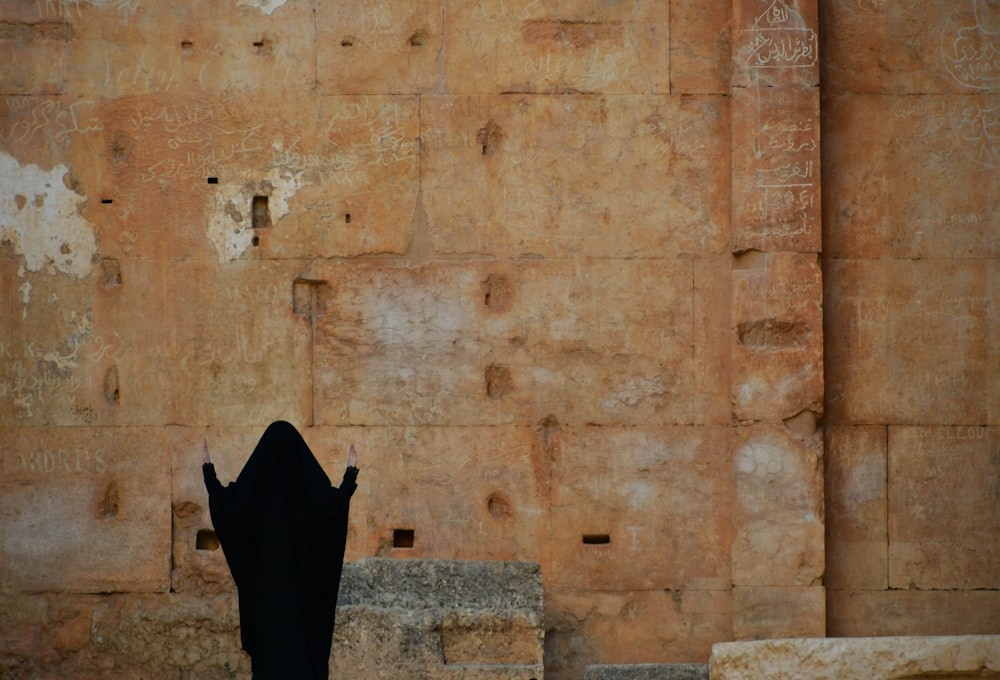 a person standing in front of a wall with writing on it