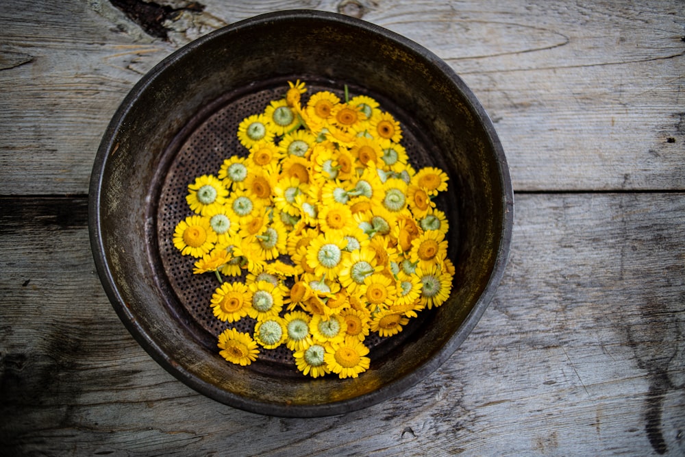 a bowl filled with yellow flowers on top of a wooden table