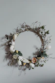 A delicate forever flower wreath with pastel roses and baby's breath hanging on a wooden door.