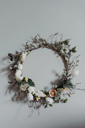 A delicate forever flower wreath with pastel roses and baby's breath hanging on a wooden door.