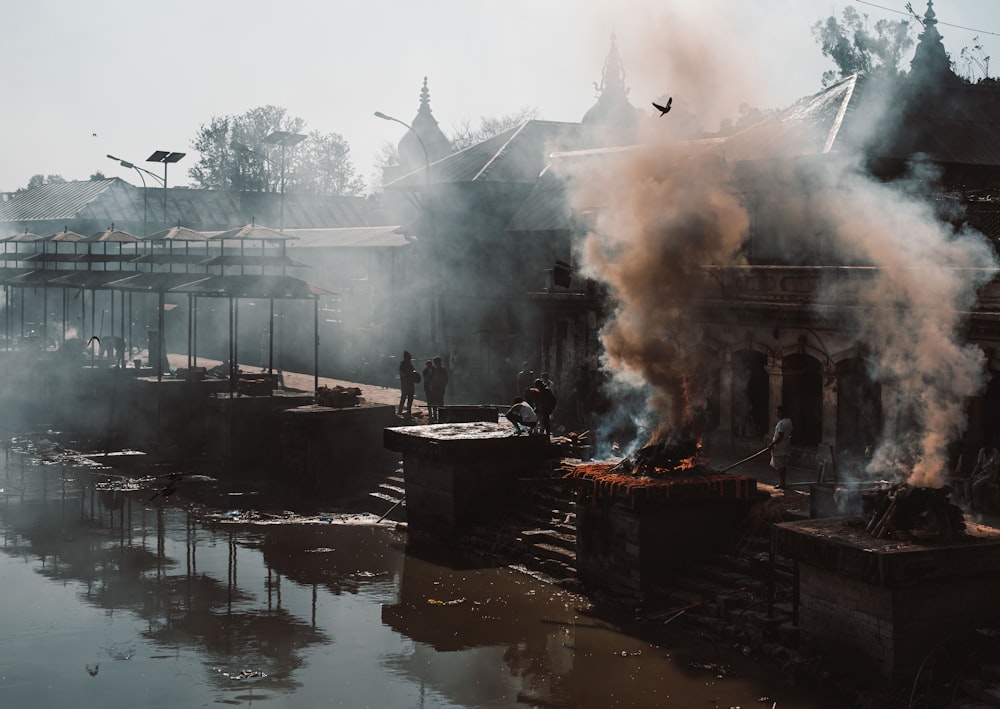 smoke billowing out of a building next to a body of water