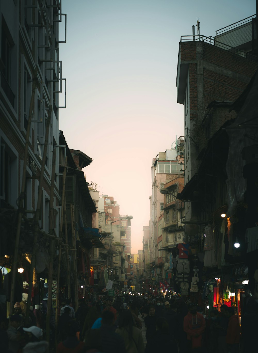 a crowd of people walking down a street next to tall buildings