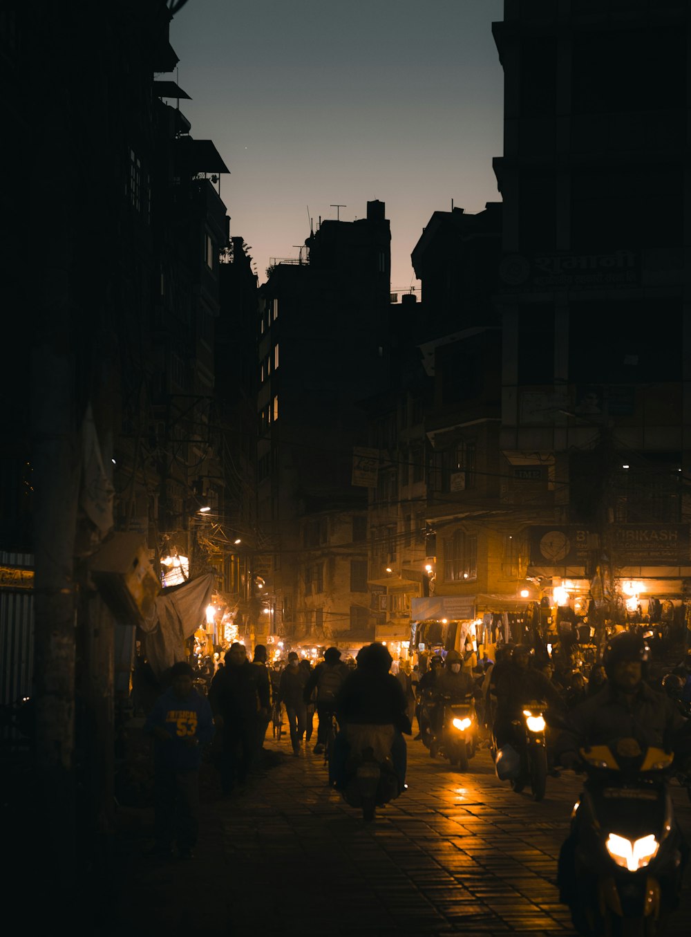 a group of people riding scooters down a street at night