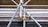 A close-up view of a complex structure made of interlocking metal scaffolding tubes and clamps. The metal is predominantly silver and grey with hints of golden brass at the joints. The scaffolding appears sturdy and is likely used in construction or maintenance work.