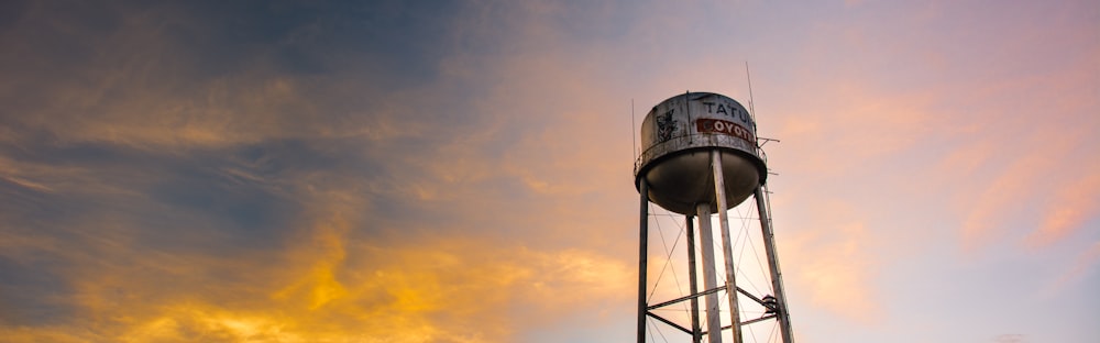 a tall metal water tower sitting under a cloudy sky