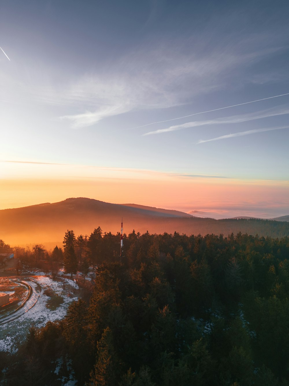 the sun is setting over a forested area