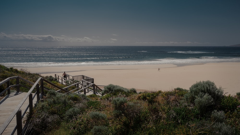 a boardwalk leading to a beach with a person standing on it