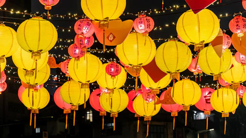A festive scene with colorful lanterns glowing warmly during a nighttime celebration.