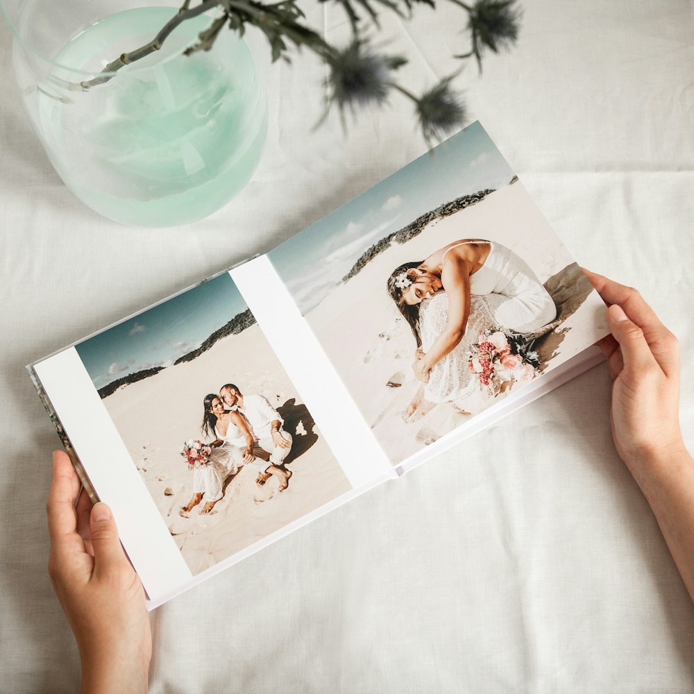 a person holding a photo book open to a picture of a bride and groom