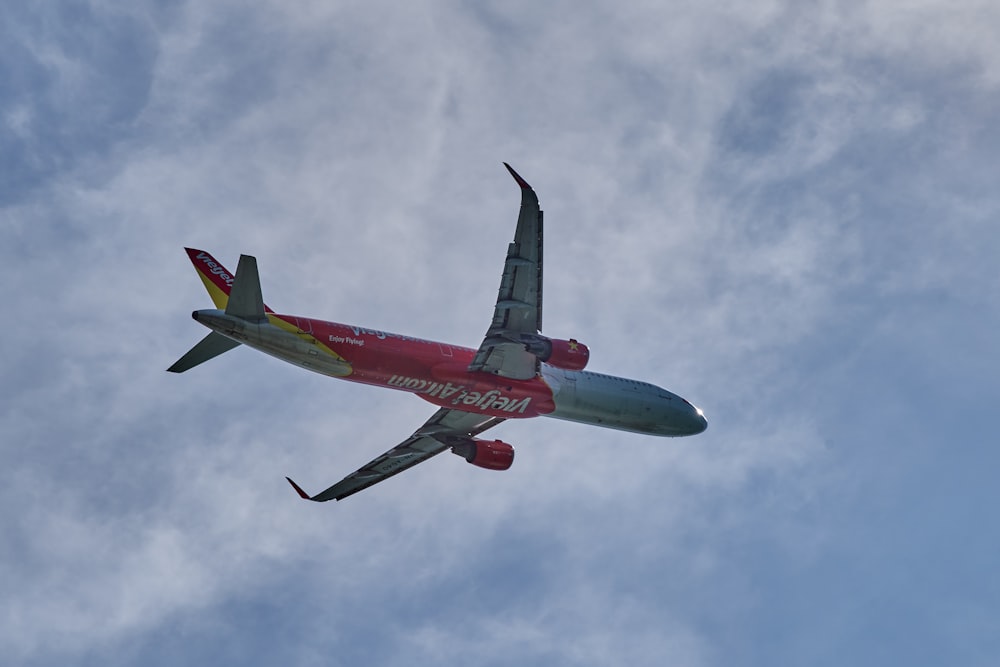 a red and green airplane flying in the sky
