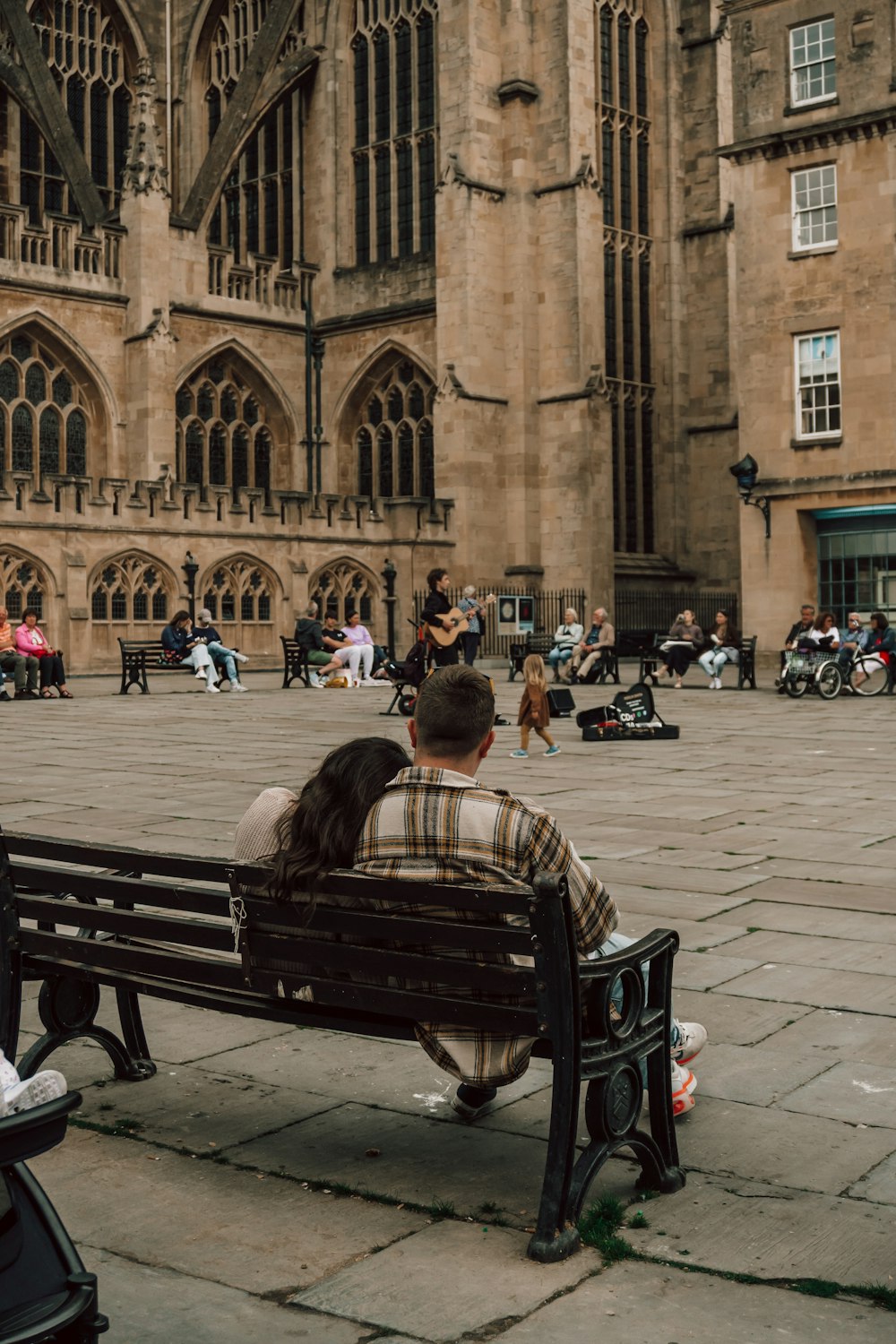 a man and woman sitting on a bench in front of a building