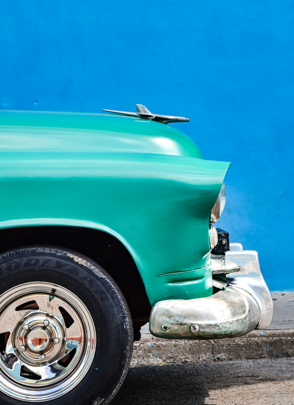 a green car parked in front of a blue wall