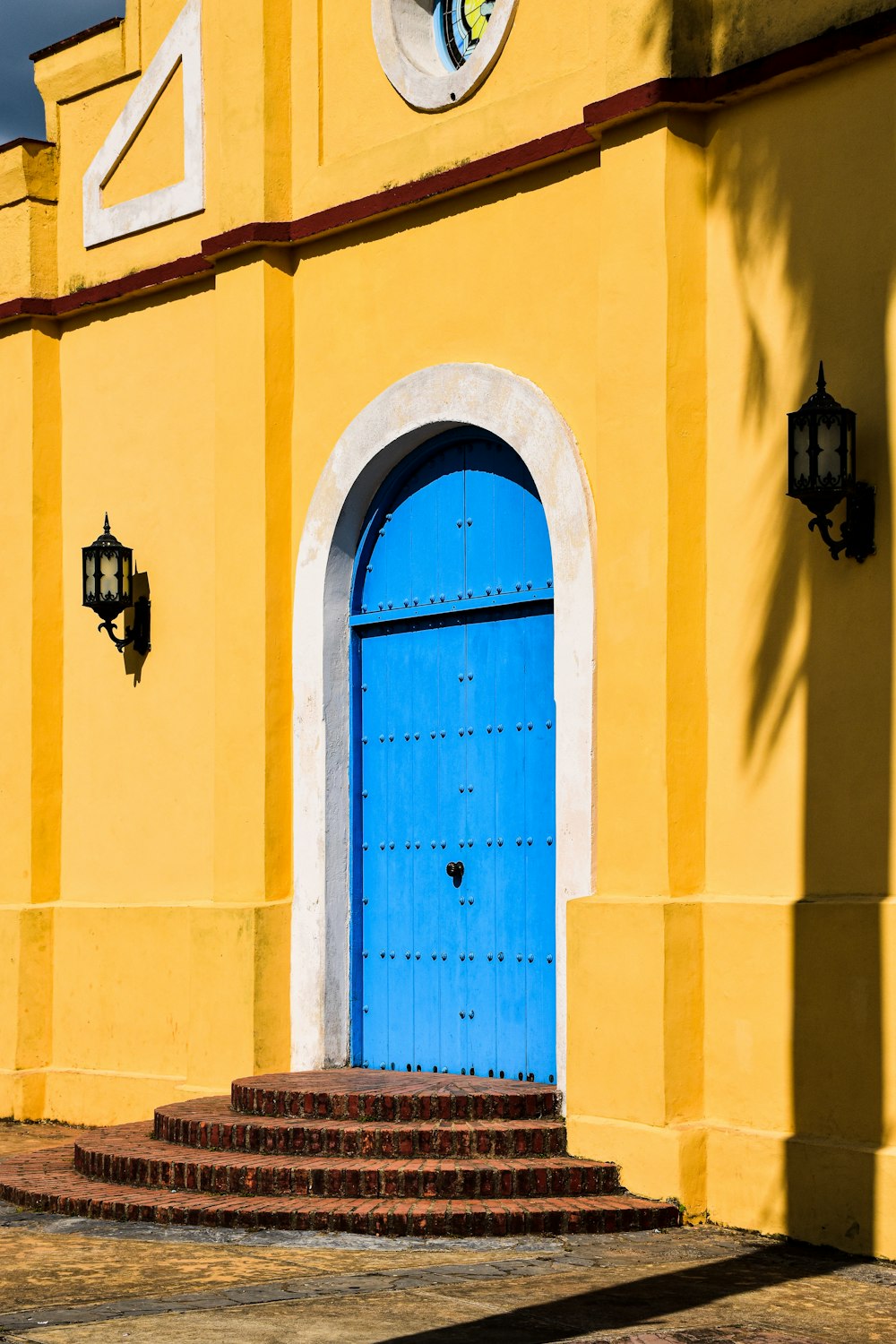 a yellow building with a blue door and steps