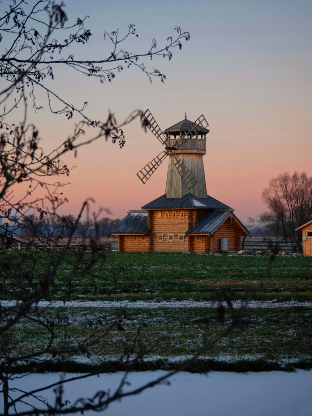 a windmill in a field next to a body of water