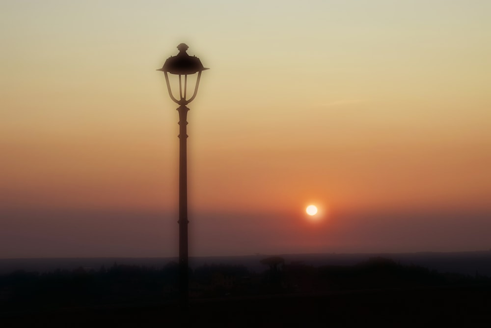 a street light with the sun setting in the background