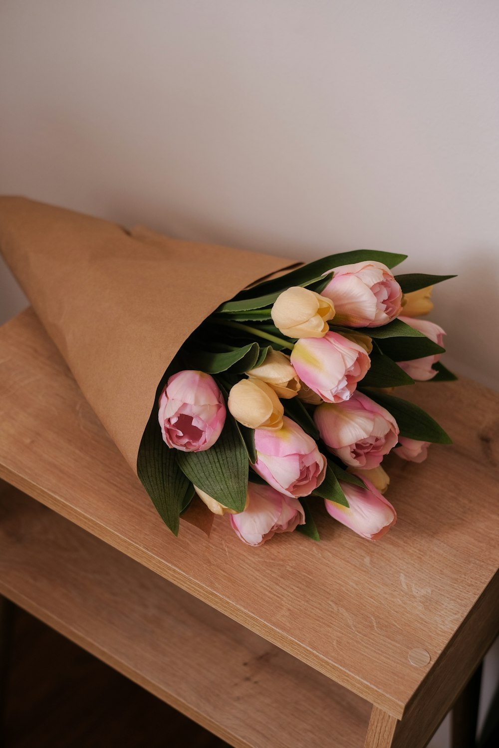 a bouquet of pink and yellow tulips on a wooden table