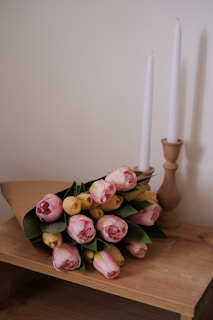 An elegant flower case with pastel tulips glowing softly under natural light on a wooden table.