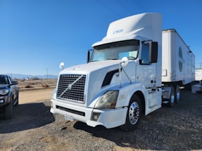 A real photo of a powerful semi-truck parked at a busy freight terminal under a clear sky.