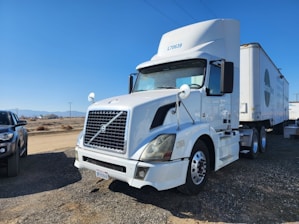 Classic semi-truck parked at a loading dock under a clear blue sky.