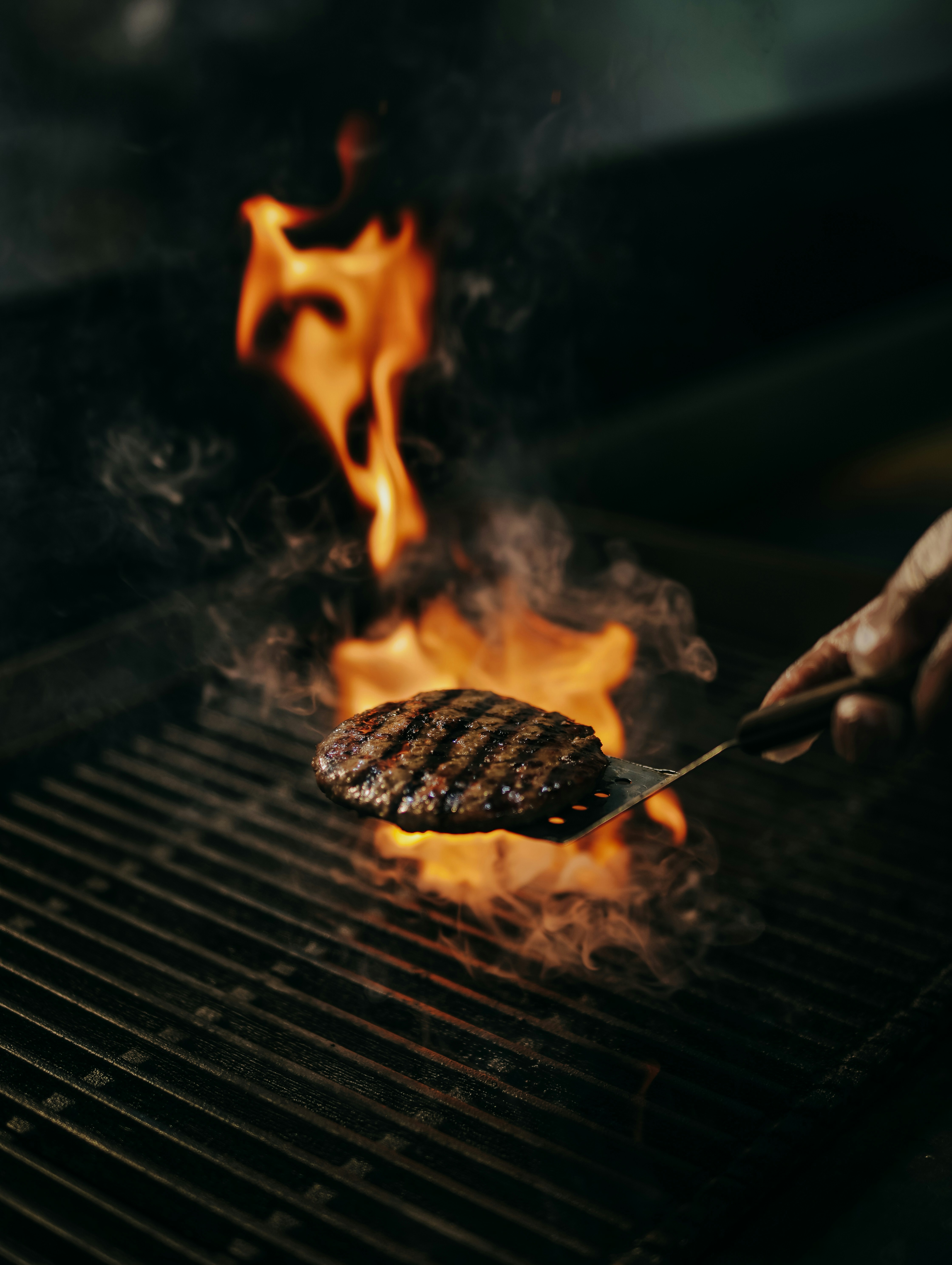 A person is grilling a hamburger on a grill photo Free Food Image on