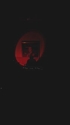 A moody portrait of Manuel G. Zaragoza in a dark room with red lighting, reflecting his thriller writing style.