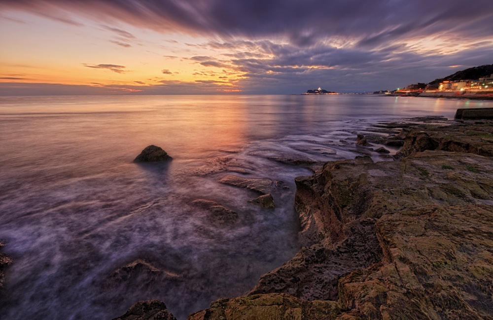 uma foto de longa exposição de um pôr do sol sobre o oceano