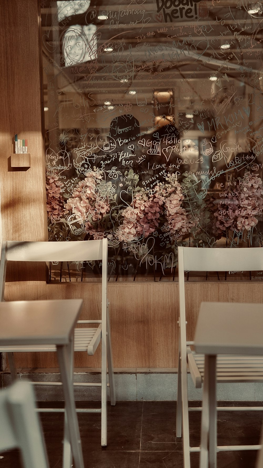 two white chairs sitting in front of a window with writing on it