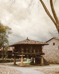 a stone building with a wooden roof next to a tree