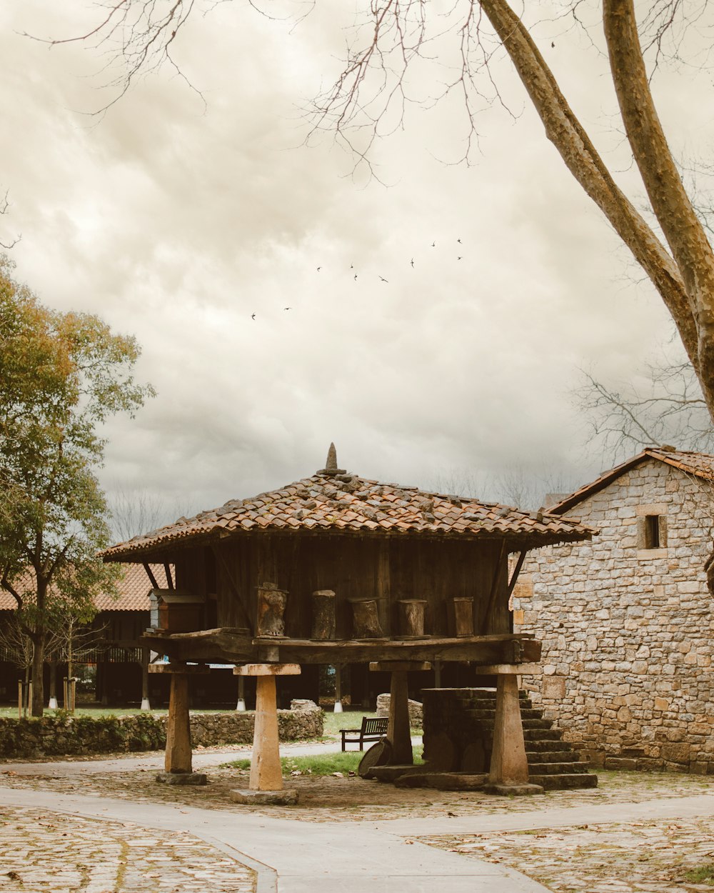 a stone building with a wooden roof next to a tree
