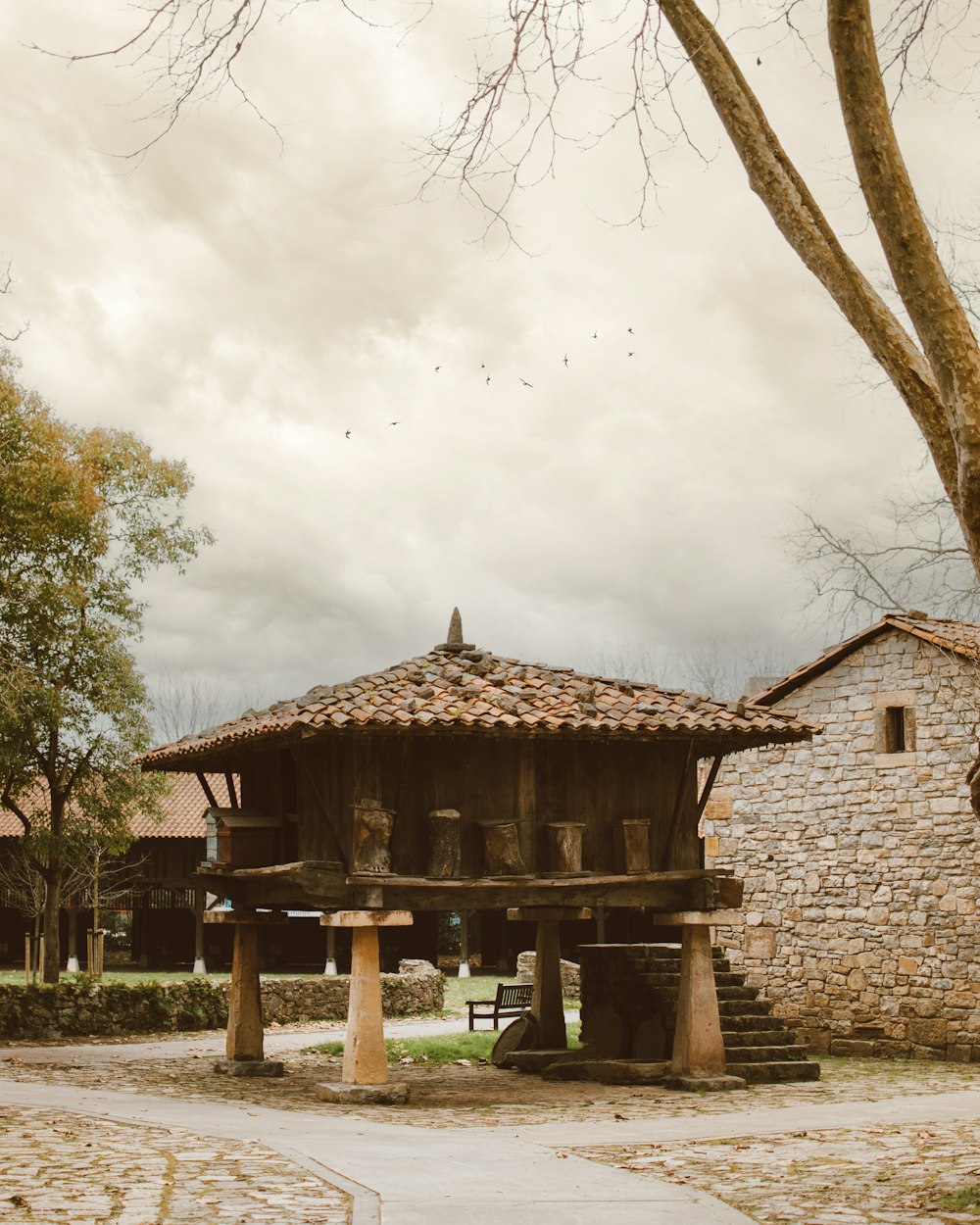 un edificio de piedra con techo de madera junto a un árbol