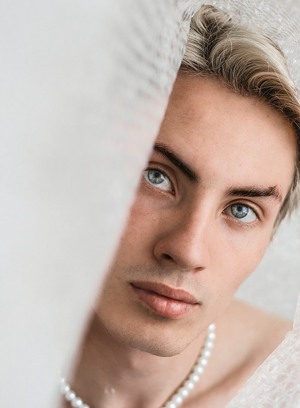 a man with a pearl necklace looking at the camera