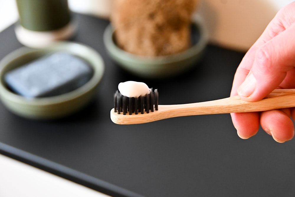 uma pessoa segurando uma escova de dentes com uma pasta de dente sobre ela