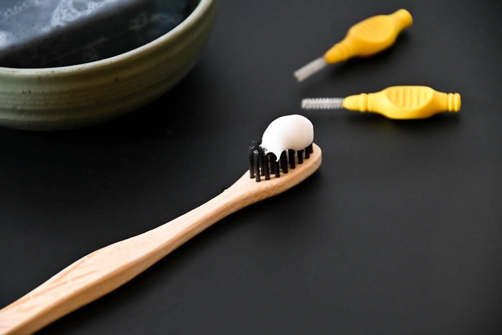 a toothbrush with a toothpaste on it next to a bowl of tooth