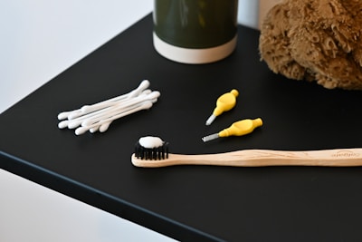 a toothbrush, toothpaste, and a teddy bear on a table