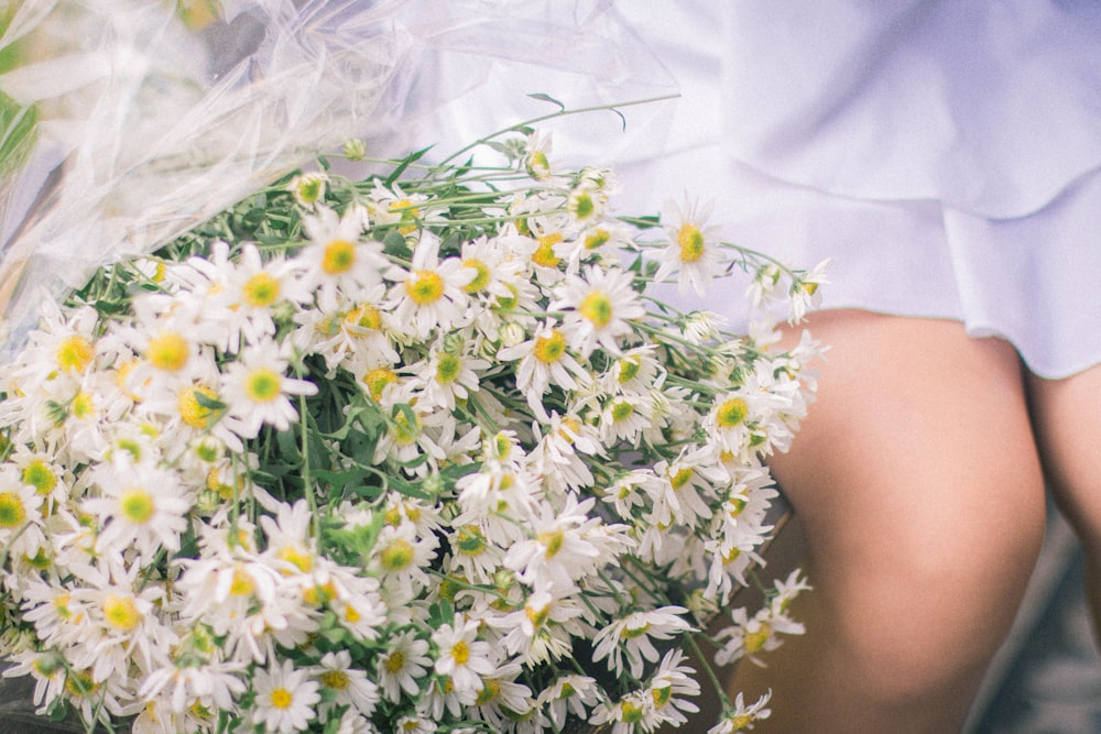 a woman holding a bouquet of white daisies