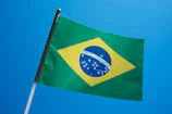 the flag of brazil is flying in the blue sky