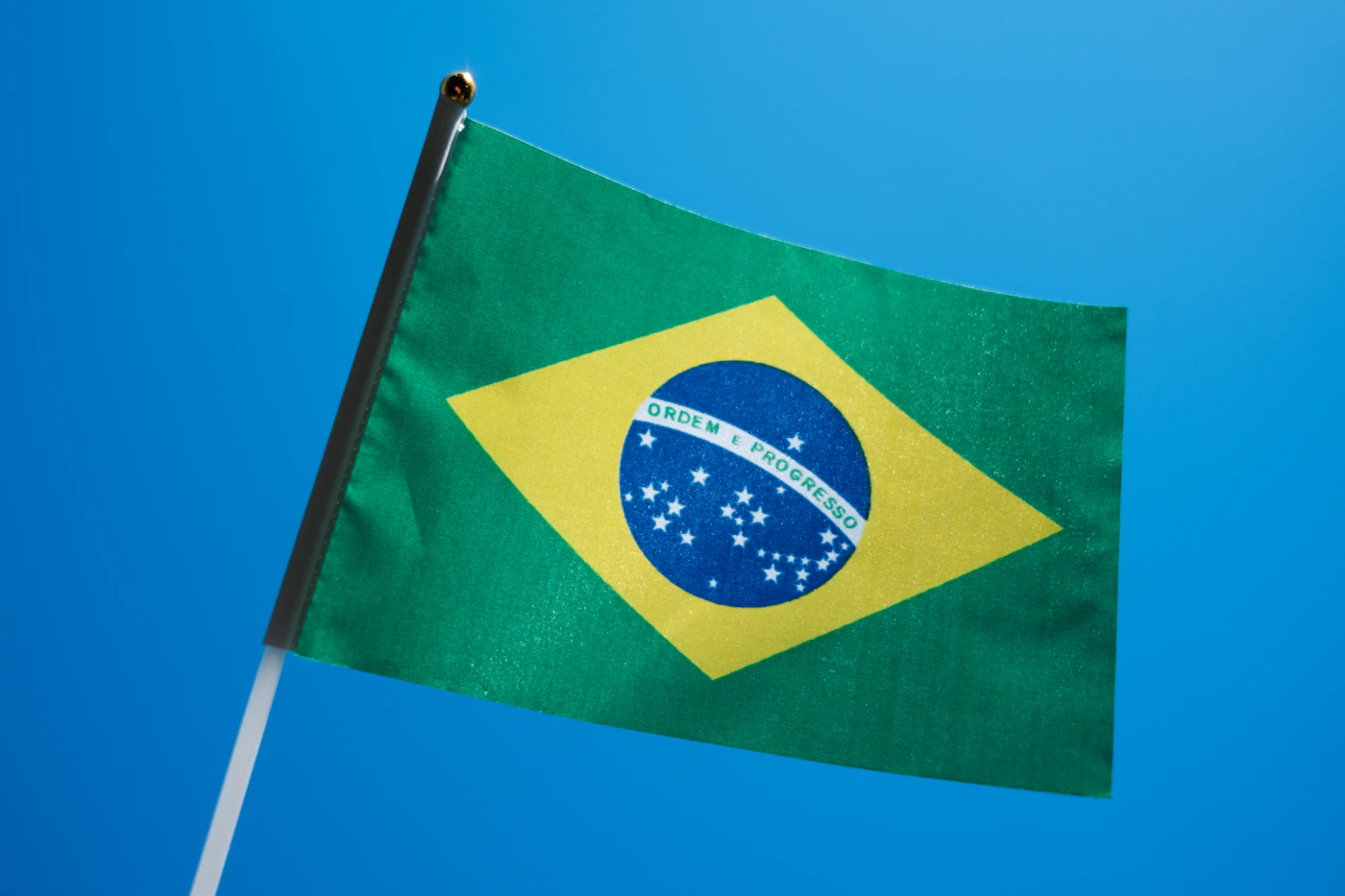 Flag of Brazil flying against a bright blue sky