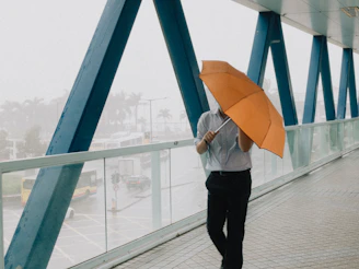 a man walking across a bridge while holding an umbrella