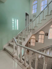 A tidy, well-lit stairwell with freshly cleaned railings and floors, bathed in soft natural light