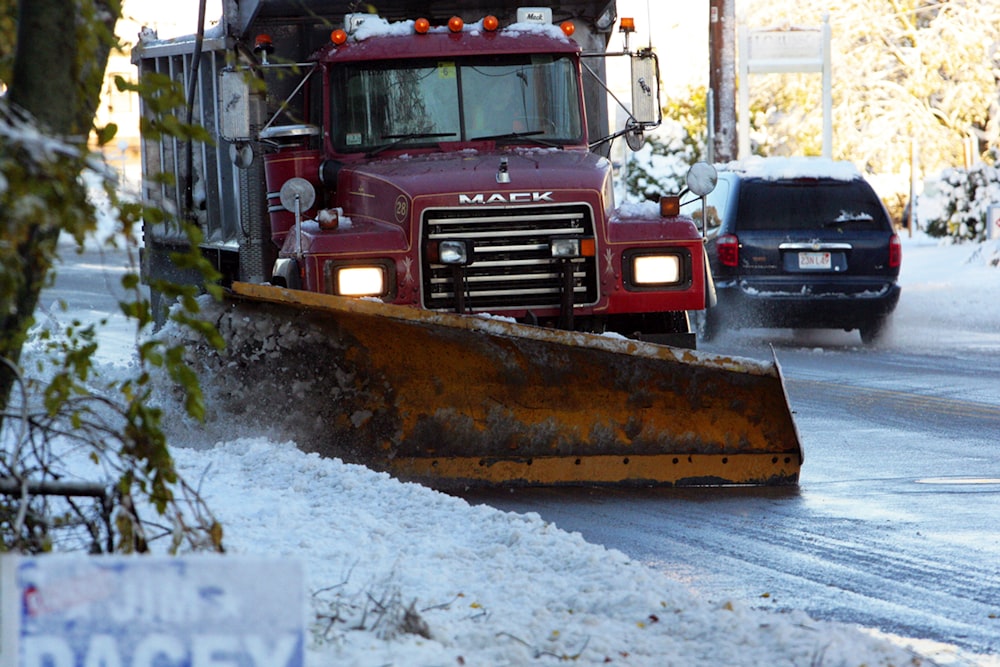 a snow plow driving down a snow covered road