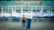 A young man and woman in school uniforms stand holding trophies in front of a school building with the sign 'SMA NEGERI 19 GARUT.' In the background, blurred figures of other students in motion create a dynamic sense of movement.