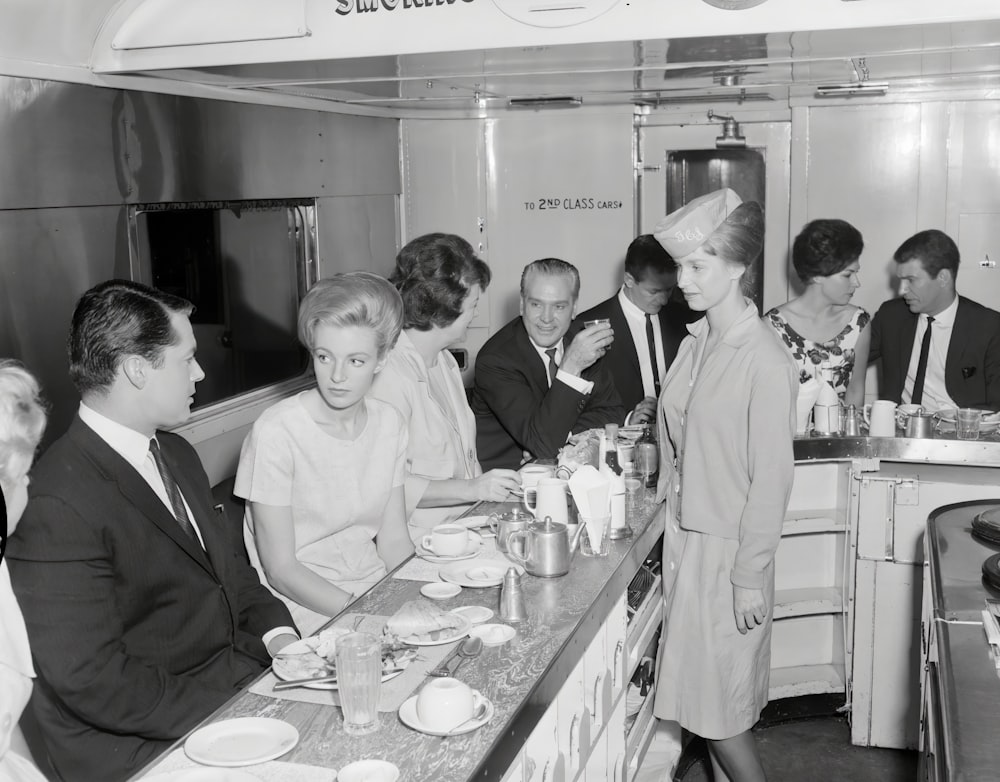 a black and white photo of a group of people eating