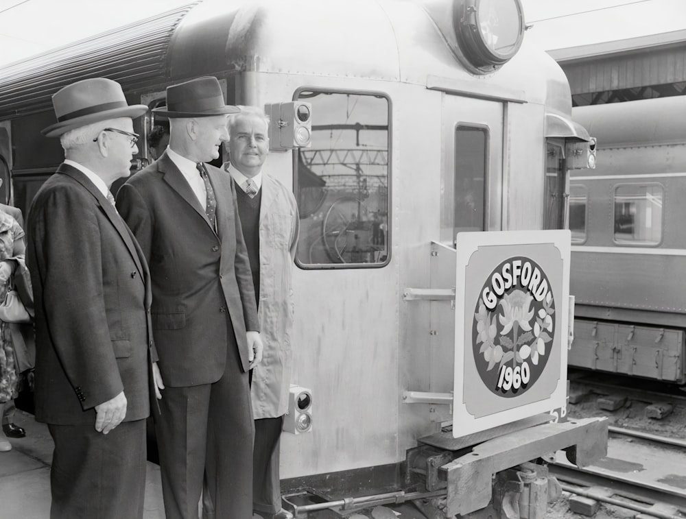 a group of men standing next to a train