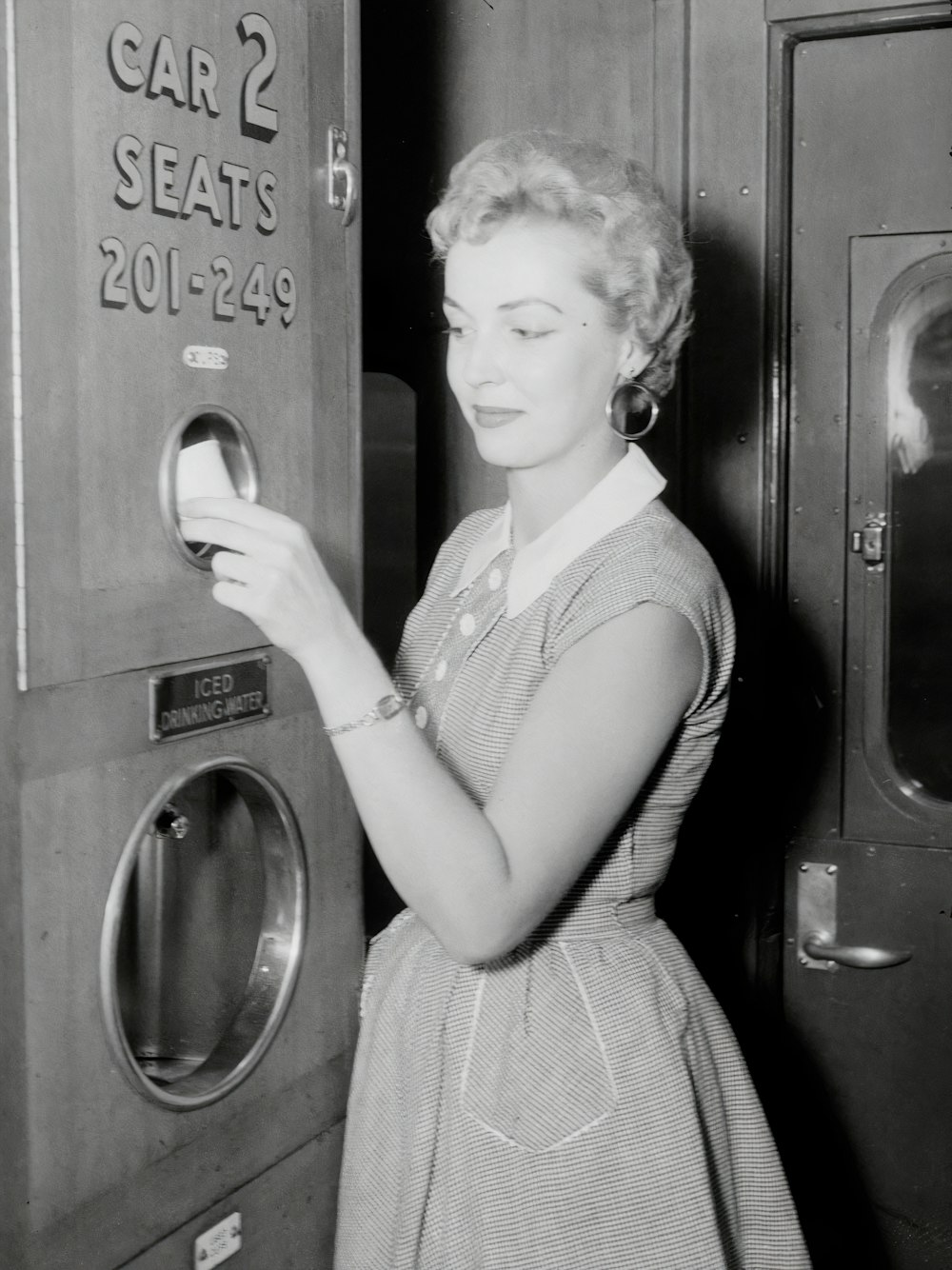 a black and white photo of a woman opening a machine