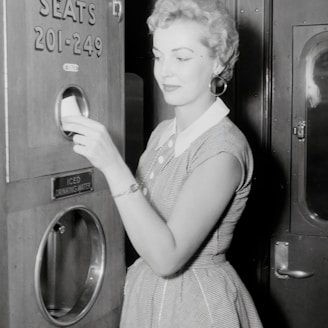 a black and white photo of a woman opening a machine