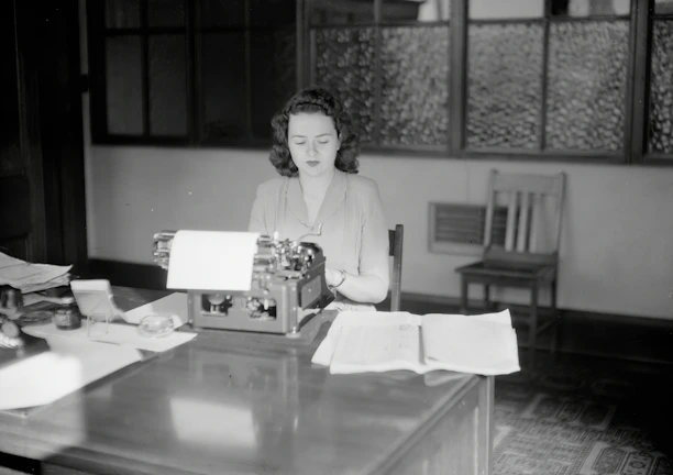 A candid photo of a journalist typing passionately at a newsroom desk.