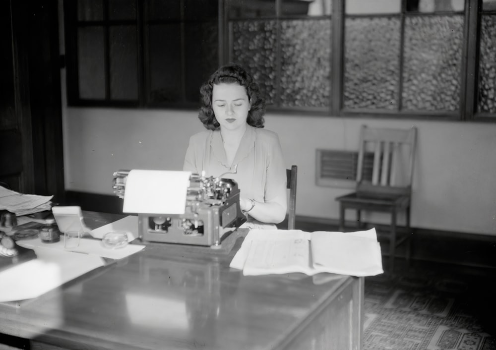 a woman sitting at a desk with a typewriter