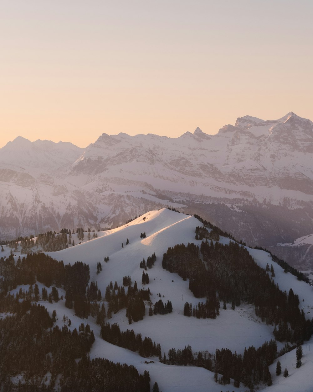 a view of a snowy mountain range at sunset