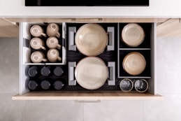 a drawer with dishes and cups inside of it