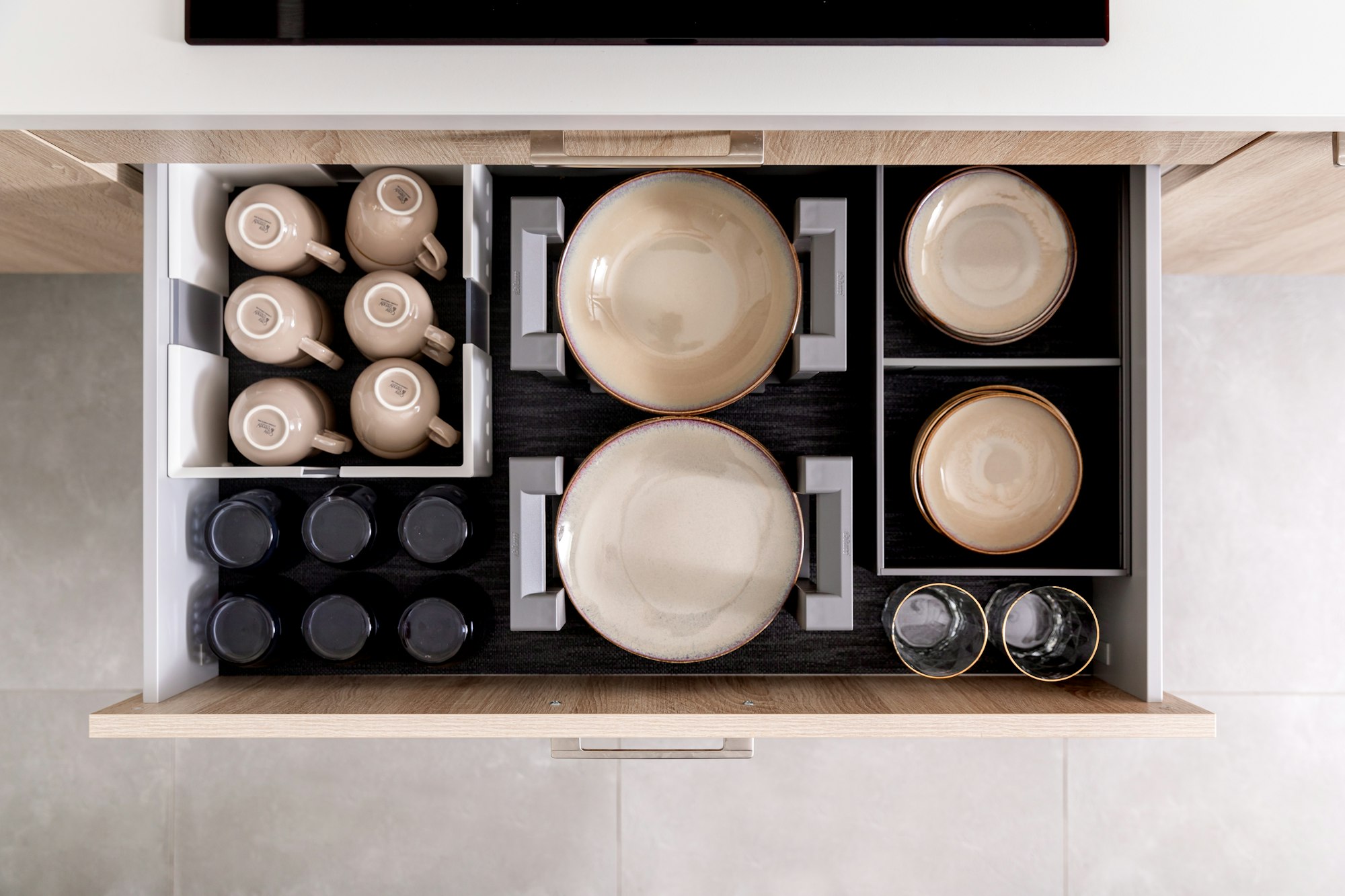 Organized kitchen drawer with plates and cups in drawer organizers.